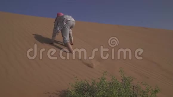 在阿拉伯联合酋长国RubalKhali沙漠沙丘坡上少女绕着沙子跑视频的预览图