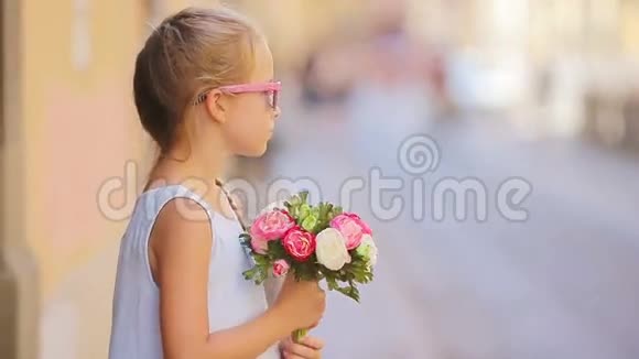 可爱的小女孩带着鲜花在欧洲城市户外散步视频的预览图