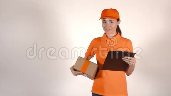漂亮的女快递员穿着橙色制服送包裹浅灰色背景4K摄影棚拍摄视频的预览图