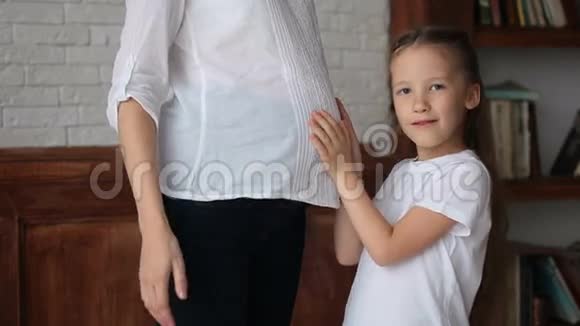 可爱的小女孩靠近她怀孕母亲的肚子视频的预览图