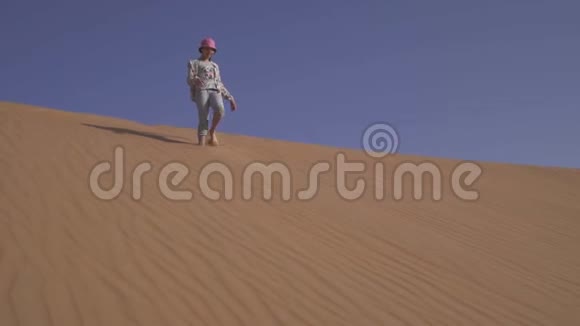 在阿拉伯联合酋长国RubalKhali沙漠沙丘坡上少女绕着沙子跑视频的预览图