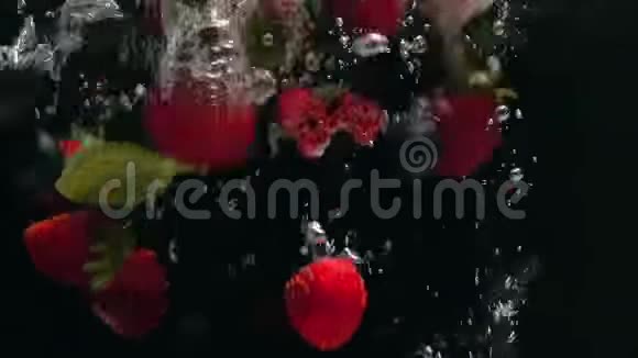 带着蓝莓和薄荷叶的新鲜覆盆子落在水中的黑色背景上溅在黑色的背景上视频的预览图