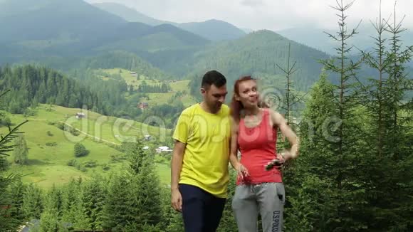 徒步情侣站在山上在阳光明媚的日子里自拍视频的预览图