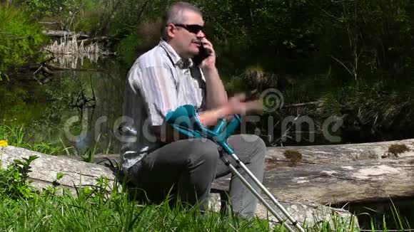 拄拐的残疾人在河边打智能电话视频的预览图
