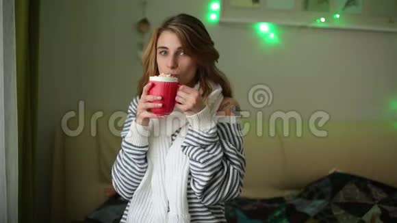 戴着围巾的年轻女人喝着红色杯子里的咖啡视频的预览图