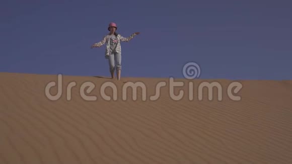 在阿拉伯联合酋长国RubalKhali沙漠沙丘坡上少女绕着沙子跑视频的预览图
