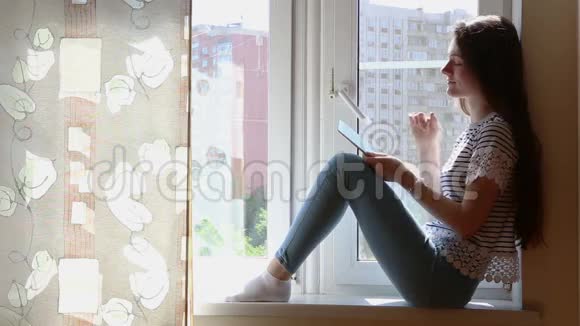窗台上有平板电脑的年轻美女视频的预览图