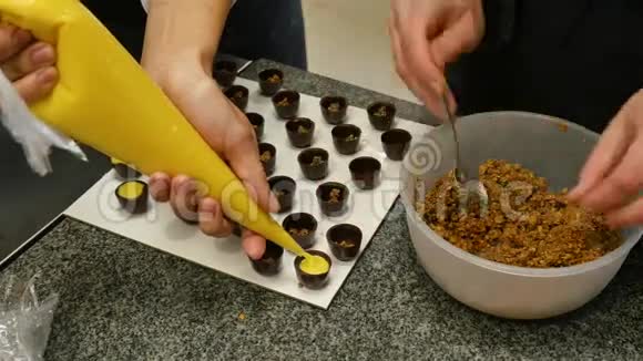 特写厨师他的手装饰巧克力奶油和坚果女人用奶油和坚果准备糖果视频的预览图