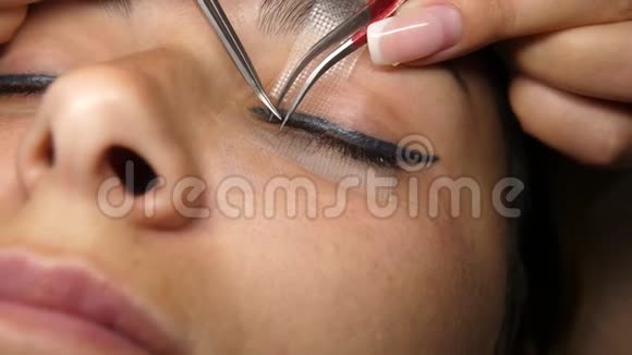 女人眼长睫毛睫毛延伸睫毛特写选定焦点把人工睫毛粘在一起视频的预览图