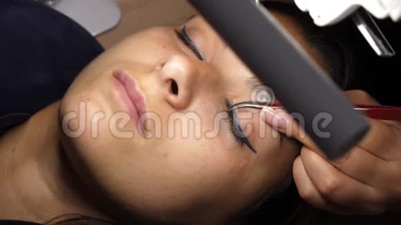 女人眼长睫毛睫毛延伸睫毛特写选定焦点把人工睫毛粘在一起视频的预览图
