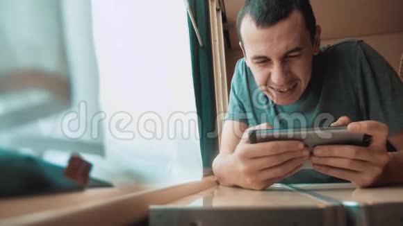 男人在智能手机上玩网络游戏强烈的情绪愤怒的男人坐在窗边的火车上慢动作视频的预览图