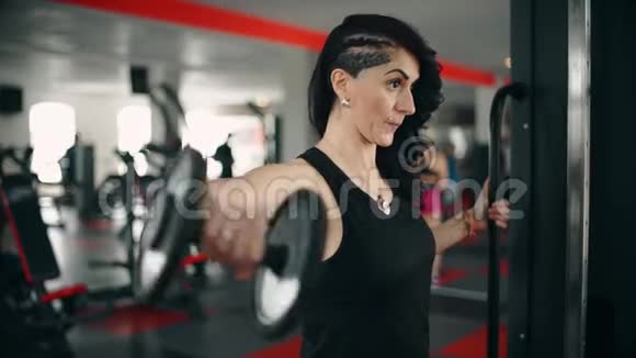 强壮的黑发女人在健身房举重视频的预览图