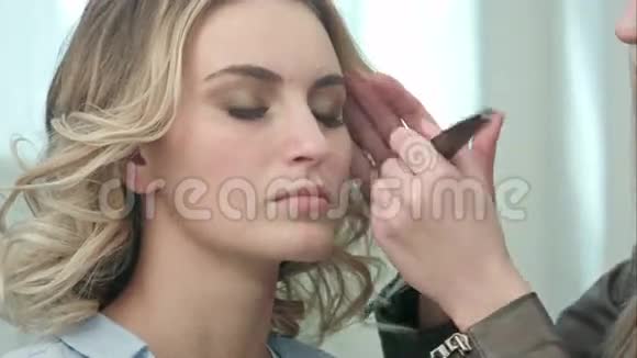 专业化妆师在年轻模特脸上涂粉视频的预览图