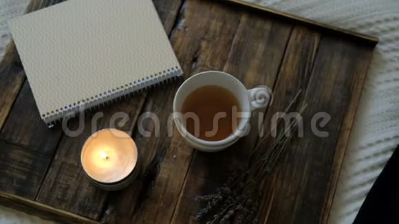 热茶在房间的木托盘上燃烧蜡烛和笔记本视频的预览图