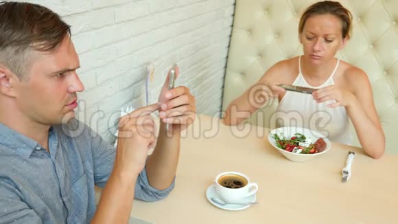 一对在咖啡馆男人和美女约会每个人都在看他的手机4k慢动作视频的预览图