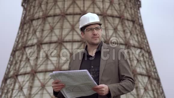 电站背景下的青年建筑师有吸引力的男性设计师拿着一幅画核冷却塔视频的预览图