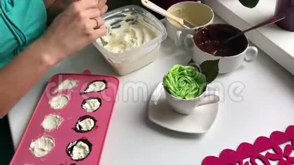 女人把凝乳放进硅胶模子里涂上融化的白巧克力和黑巧克力做甜点视频的预览图