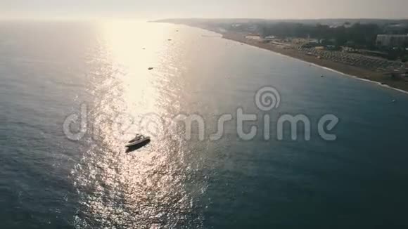 在阳光明媚的一天空中观景快艇在平静的水中漂浮在海岸附近水面上的太阳反射视频的预览图