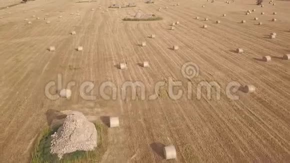 用干草球和石头建筑对收获的麦田进行空中飞行视频的预览图