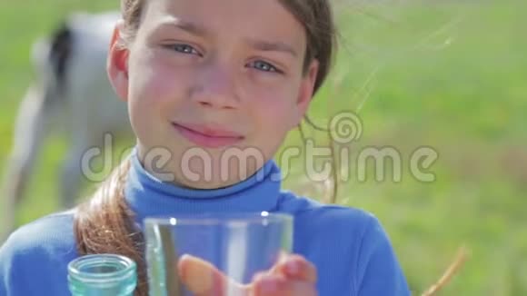 一个男孩在草地上拿着一瓶牛奶的肖像一个男孩在田里的奶牛旁边喝牛奶健康的生活方式视频的预览图
