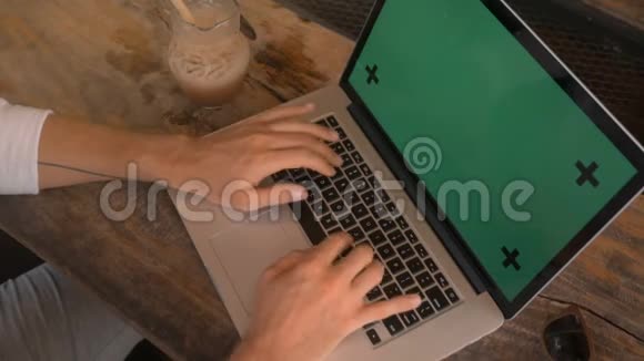 在咖啡厅用绿色屏幕的笔记本电脑上工作的男性双手特写视频的预览图