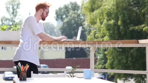 忙着在笔记本电脑上工作站在办公室室外阳台上手势视频的预览图