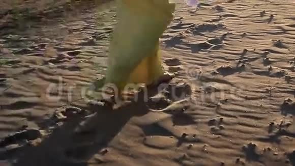 穿着黄色衣服的女人在海滩上散步视频的预览图
