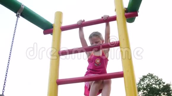 可爱的小女孩爬上操场的梯子视频的预览图
