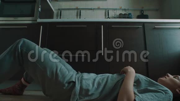 快速反射的女人躺在基琛地板上坐起来抓住掉下来的玻璃视频的预览图