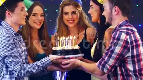 女孩和朋友一起庆祝生日在蛋糕上吹蜡烛4k视频的预览图