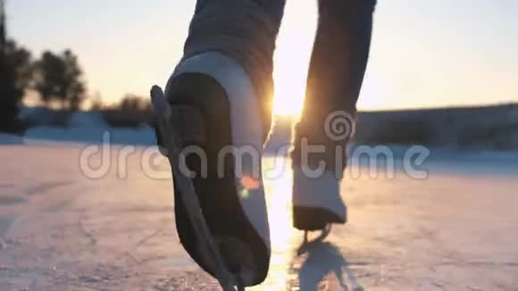 特写低角度视角快乐的女人在当地公园冰冻的池塘上快速滑冰在金色的日落下在神奇的圣诞节视频的预览图