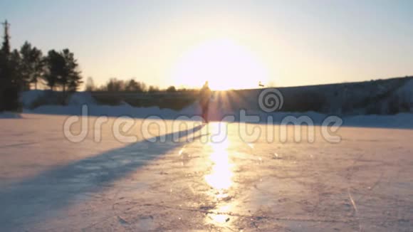 特写低角度视角快乐的女人在当地公园冰冻的池塘上快速滑冰在金色的日落下在神奇的圣诞节视频的预览图