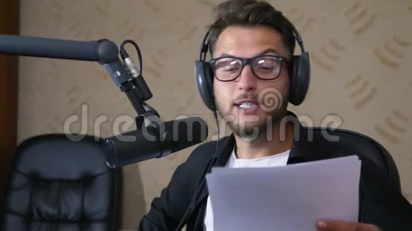 戴着眼镜和耳机的收音机主持人用麦克风讲话视频的预览图