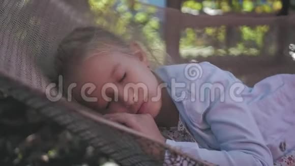 可爱的女孩躺在吊床上在花园里放松视频的预览图