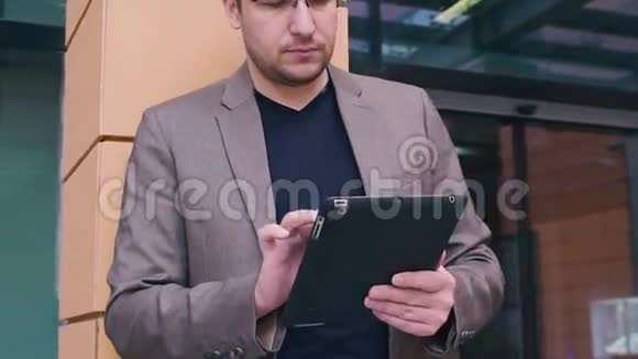 自信的商人在做平板电脑穿着夹克和眼镜的现代商业背景下的人视频的预览图