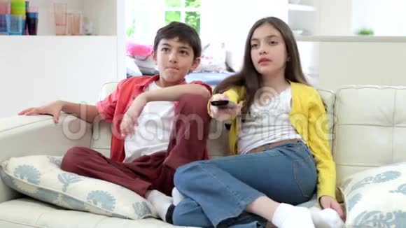 两个西班牙儿童坐在沙发上一起看电视视频的预览图