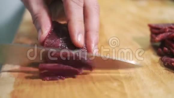 在一块木板上用一把刀把生肉切成薄片视频的预览图