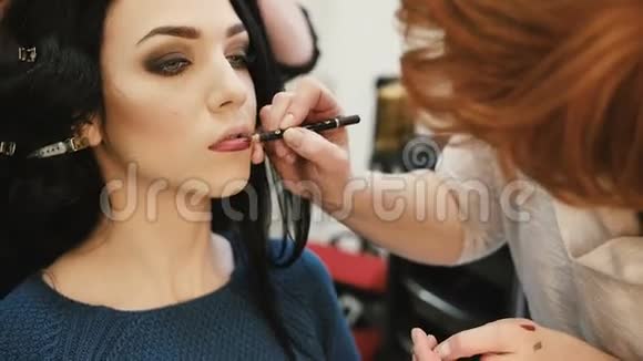 化妆师用唇笔勾出年轻女子的嘴唇视频的预览图