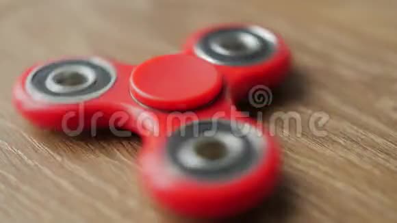 红色坐立不安的旋转器在一张木桌上旋转视频的预览图