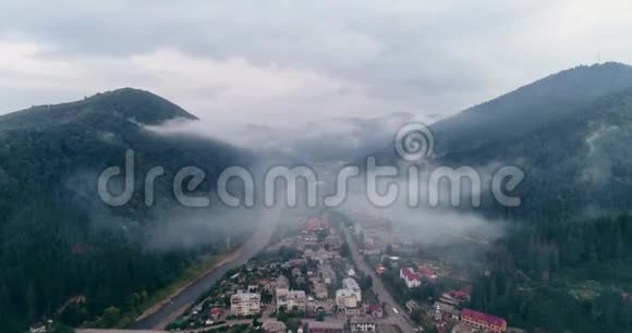 鸟瞰雾蒙蒙的森林在横贯喀尔巴阡山脉的城市Mizhgirja穿云飞行视频的预览图
