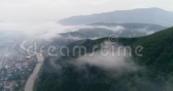 鸟瞰雾蒙蒙的森林在横贯喀尔巴阡山脉的城市Mizhgirja穿云而过视频的预览图