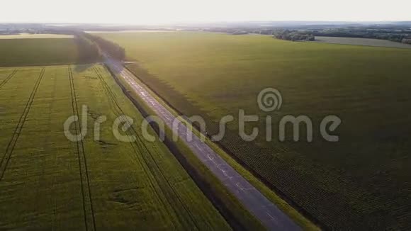 空中射击在夏天的傍晚在空旷的乡间小路上在黄绿的田野间飞翔视频的预览图