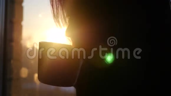 美丽的女孩在城市的夕阳下靠窗喝咖啡3840x21604k视频的预览图