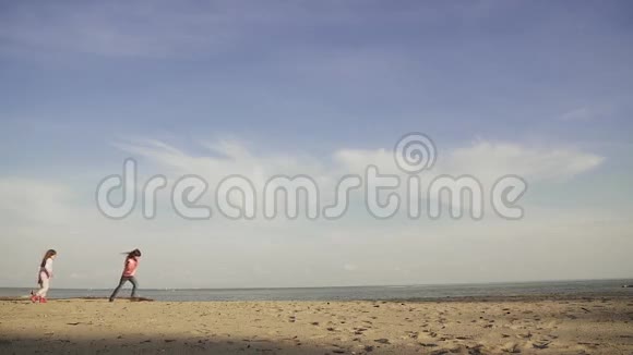 孩子们沿着沙滩奔跑两个小女孩在海边玩早春慢动作视频的预览图