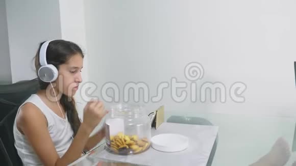 技术和娱乐的概念积极快乐的少女在家放松坐在桌子旁视频的预览图