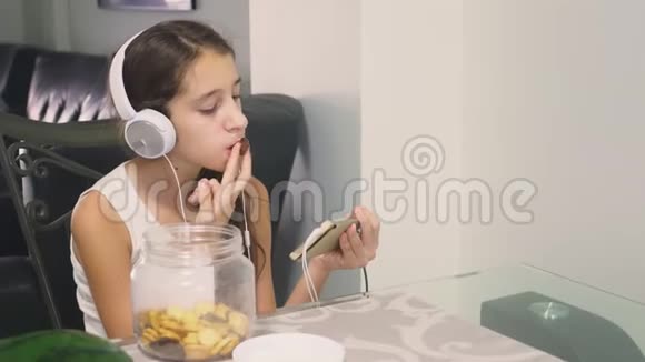 技术和娱乐的概念积极快乐的少女在家放松坐在桌子旁视频的预览图