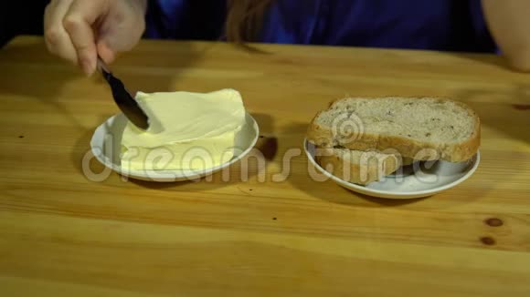 准备三明治的年轻女人把黄油涂在面包上视频的预览图