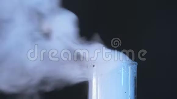 玻璃烧瓶与化学物质和干冰在黑暗的背景蓝色液体在辐射筒中的化学反应视频的预览图