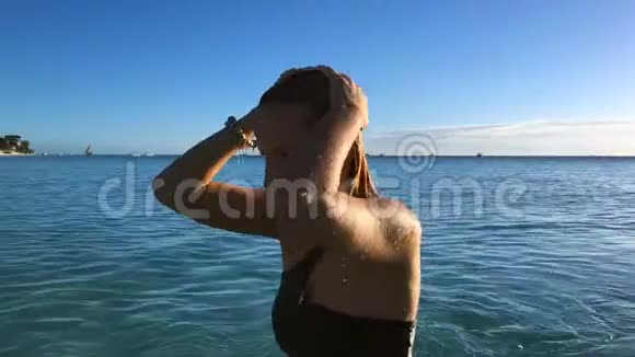 一个穿比基尼的女孩在一个孤独的热带海滩日落时在印度洋游泳视频的预览图