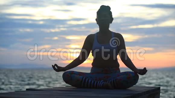 在太阳升起的天空中冥想瑜伽的女人视频的预览图